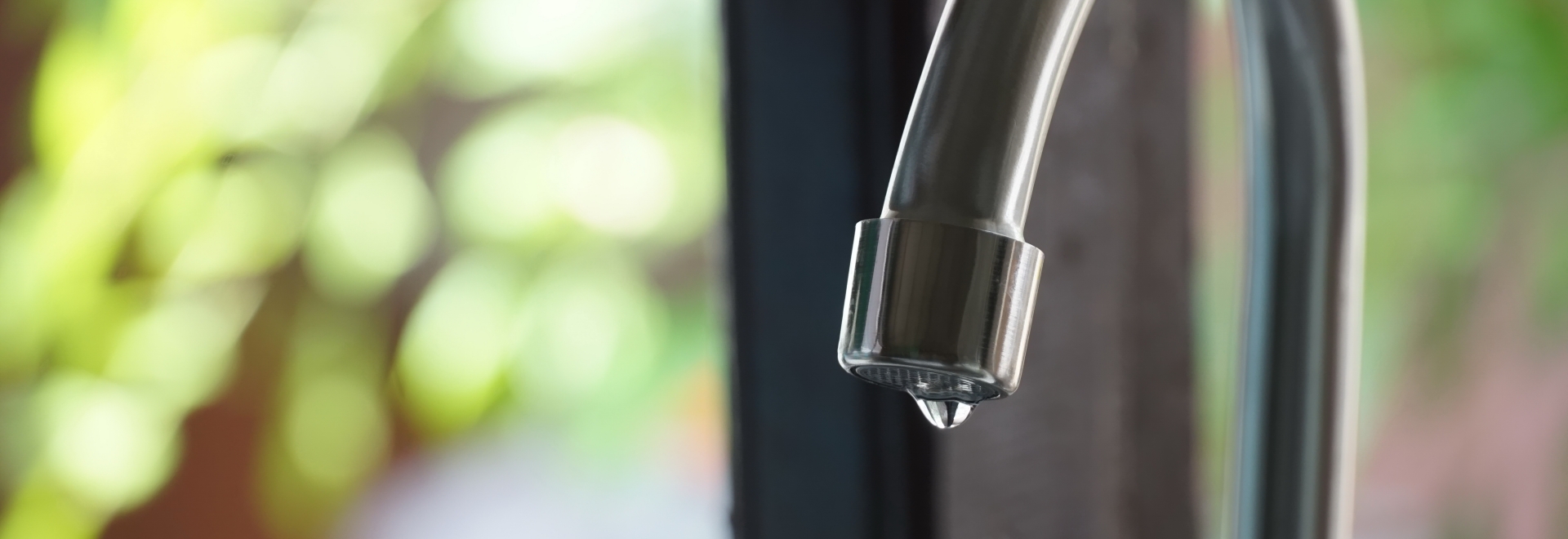 Water droplet hanging off edge of kitchen faucet spout