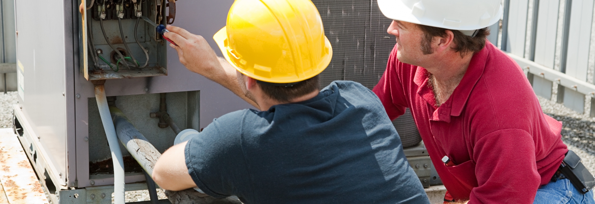 hvac technician and apprentice repairing industrial ac compressor