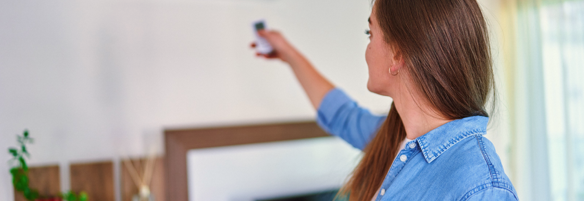 woman adjusting temperature of heat pump with a remote control at home