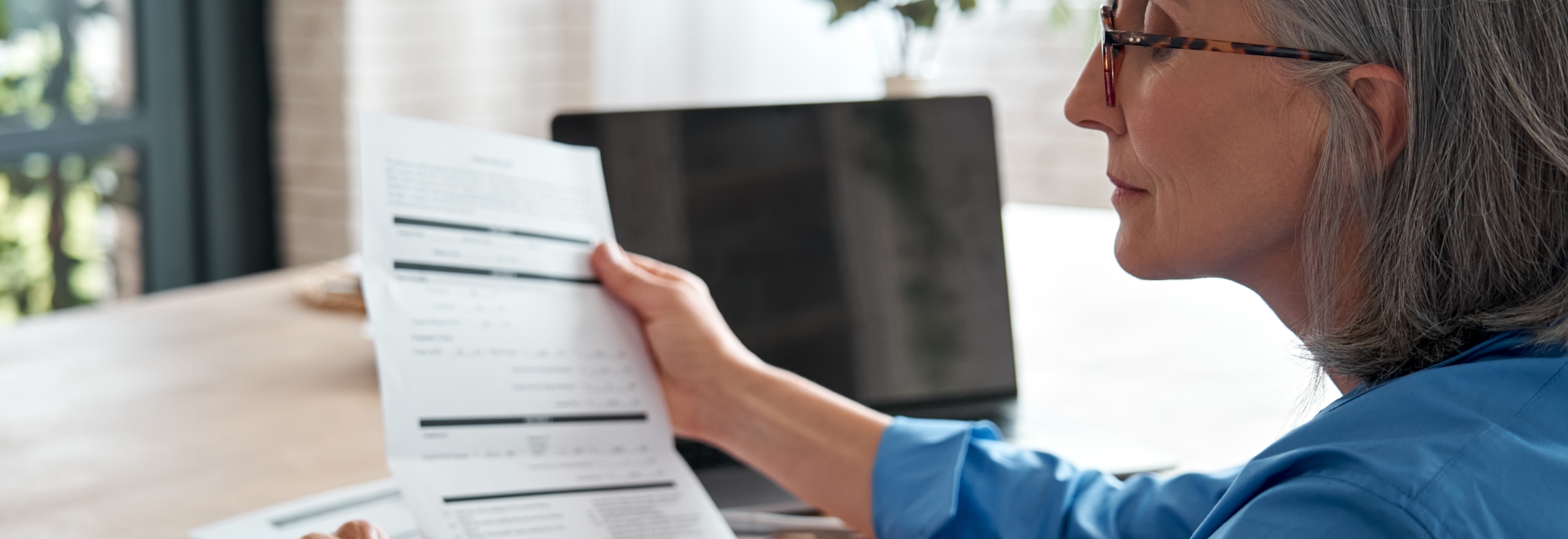 woman holding a tax form and using a calculator