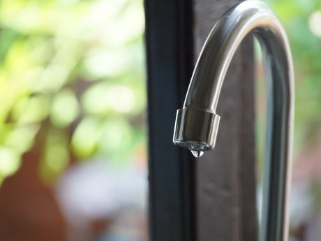 Water droplet hanging off edge of kitchen faucet spout