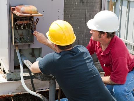hvac technician and apprentice repairing industrial ac compressor