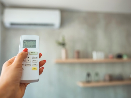 person pointing a remote at their heat pump