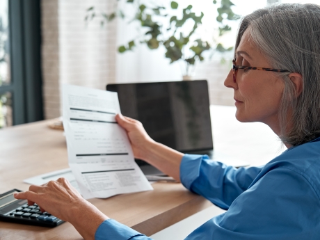 woman holding a tax form and using a calculator