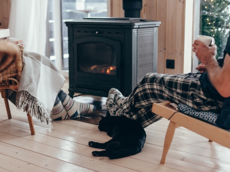 people warming up by the fire with their cat