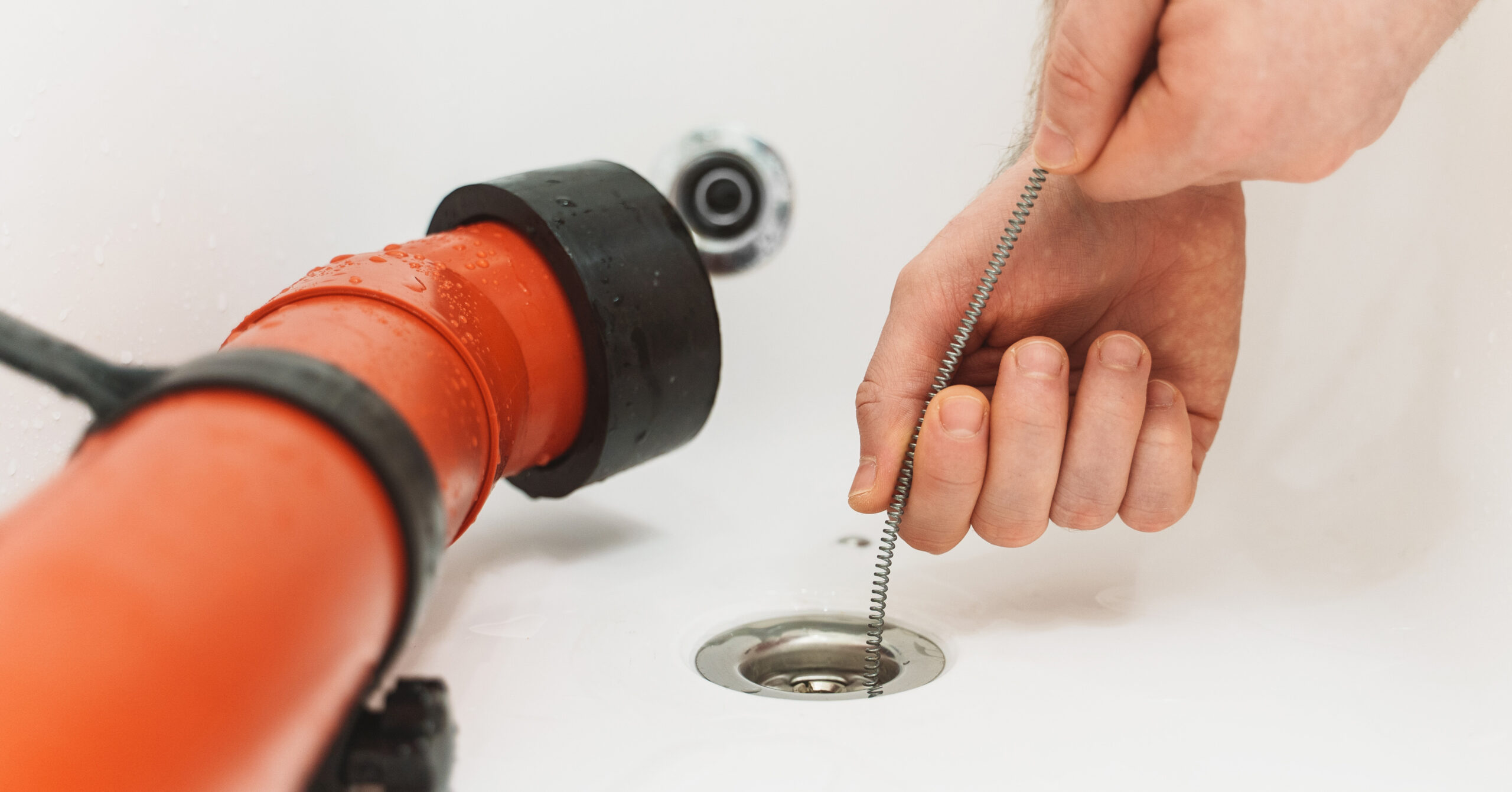A plumber puts a drain snake in a bathtub. Plumbers can provide drain cleaning tips to New Jersey homeowners to avoid bad smells.