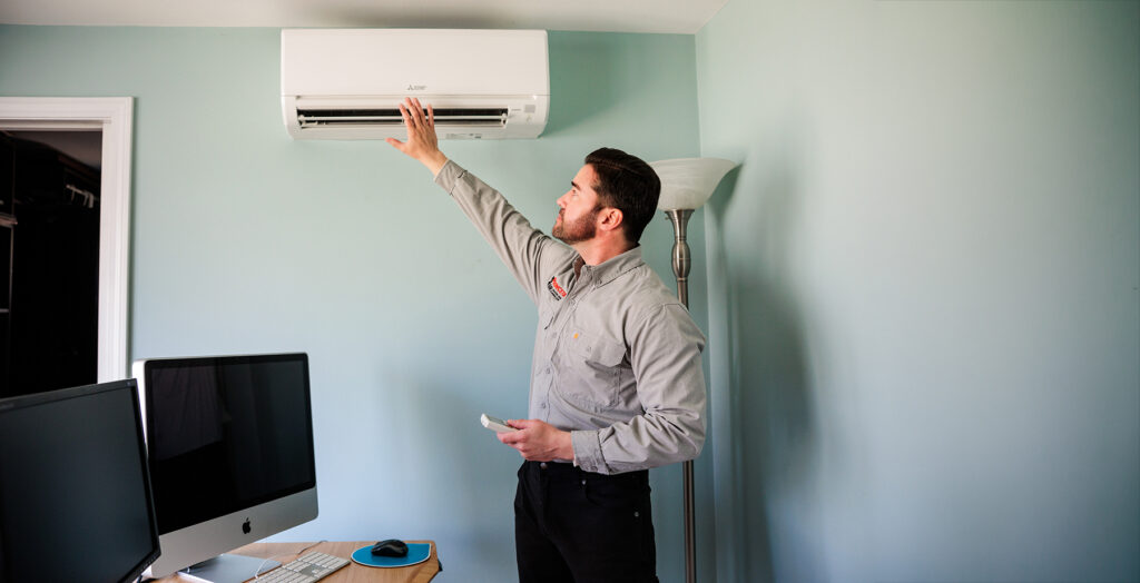 a princeton air tech is testing a ductless mini split remote and fan in a house