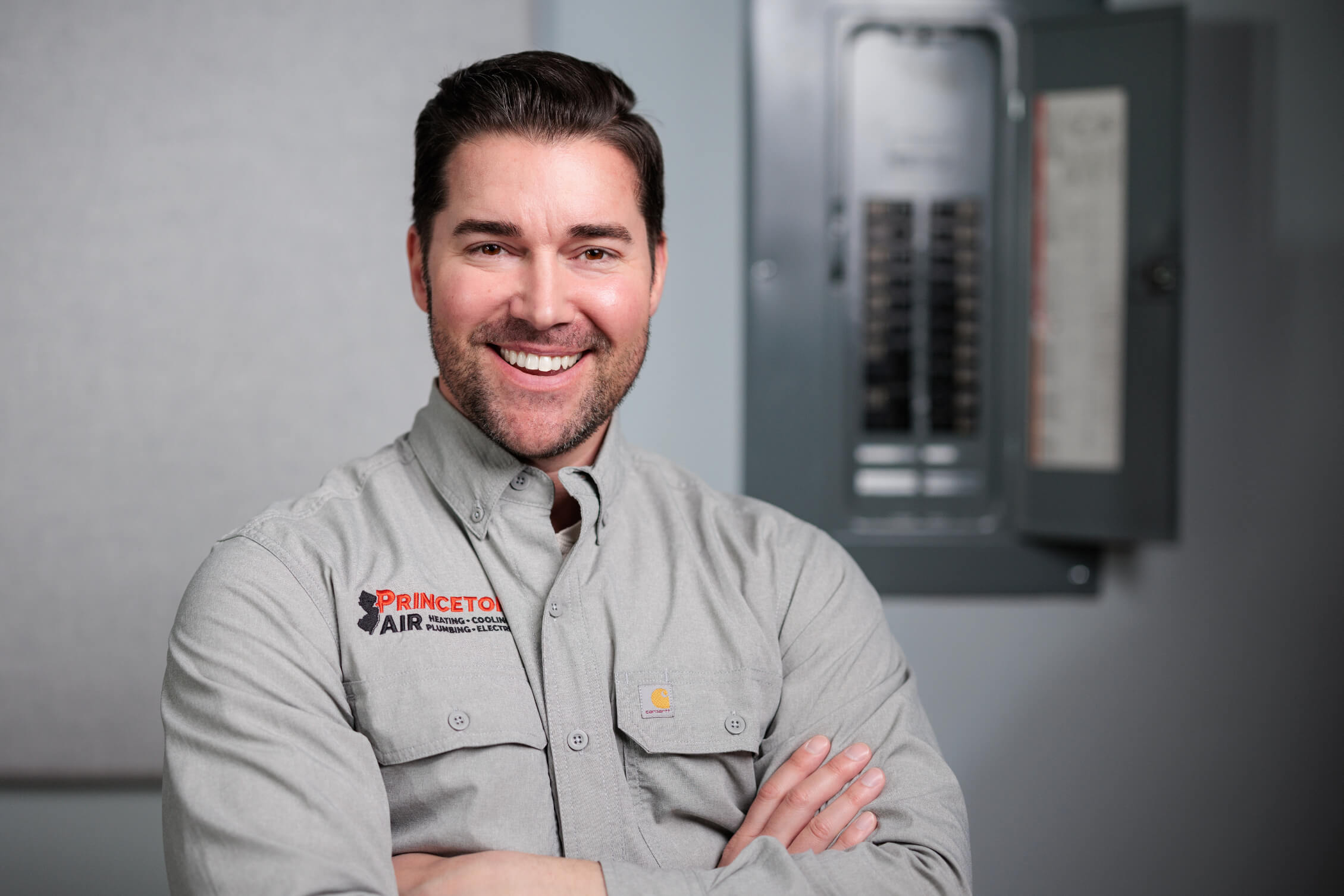 Smiling PA electrician beside panel